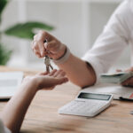 A new landlord receives a house keys chain from a real estate br